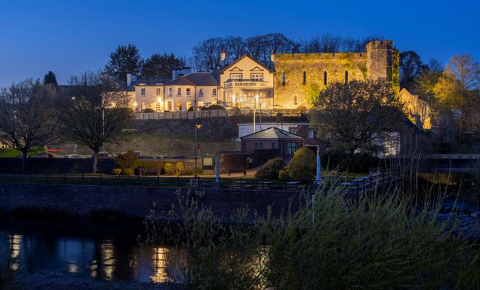 Exterior shot of a hotel at night next to a river.